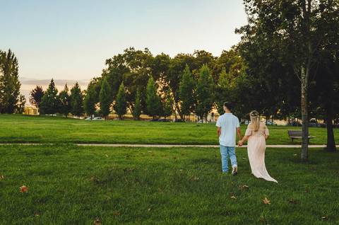 Casal em parque com mulher grávida ao pôr do sol'