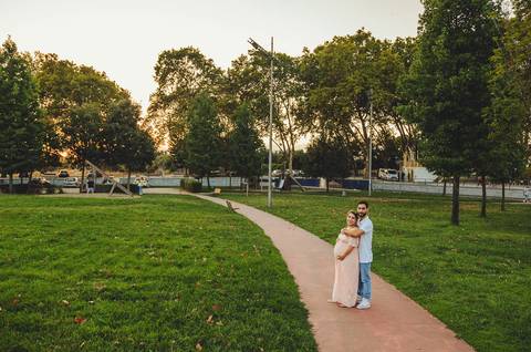 Casal no parque em dia ensolarado com gravidez visível'