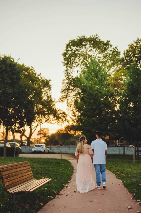 Casal em árvore ao entardecer com mulher grávida central'