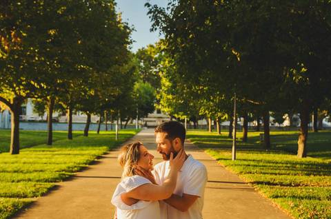 Casal em parque verde com gestante em primeiro plano'