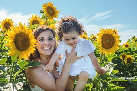 Menina em retrato familiar brincando em campo de girassóis ao ar livre. Criança em sessão fotográfica profissional com ambiente natural de fundo. Fotografia capturando momentos autênticos de infância em composição artística natural.'