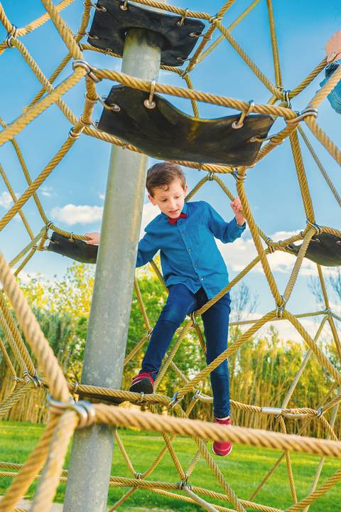 Menino em estrutura de pneus escalando no parque'