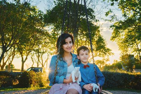 Mãe e filho brincando em paisagem natural ao pôr do sol'