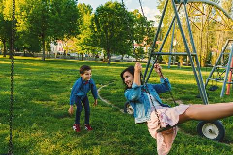 Menino escalando em estrutura do parque com alegria'