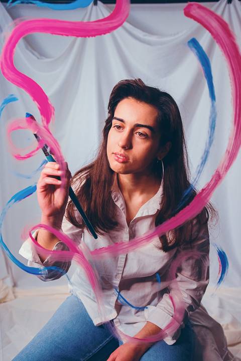 Retrato com pintura facial vívida em tons de rosa e ciano'