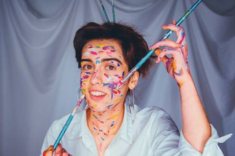 Retrato de mulher com expressão alegre e pincéis na mão'