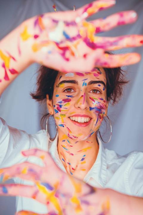 Mulher jovem sorridente com pintura facial colorida'