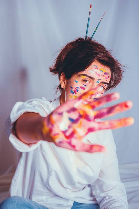 Mulher com pintura facial alegre mostrando mãos na cabeça'