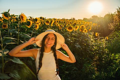 Retrato feminino em campo de girassóis com luz dourada do entardecer'