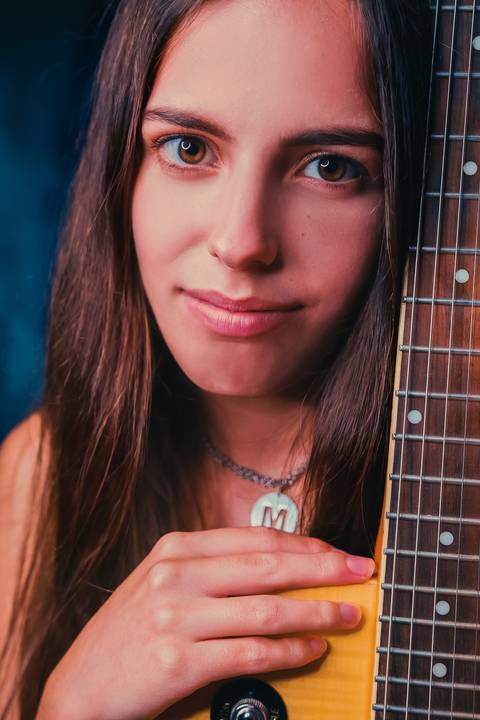 Retrato sorridente de mulher com violão ao peito'