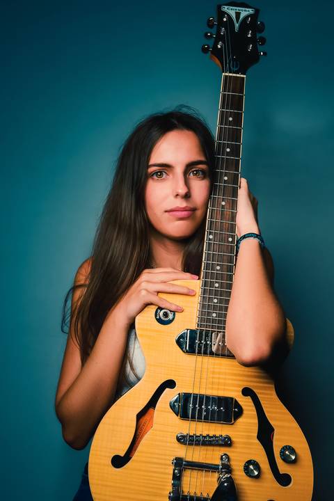 Mulher com violão em fundo azul estúdio profissional'