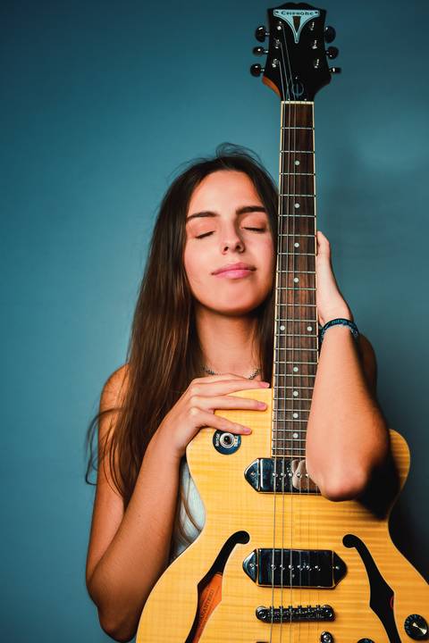 Retrato artístico com violão em fundo azul iluminado'