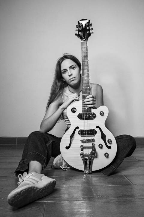 Retrato preto e branco com violão deitada em pose artística'