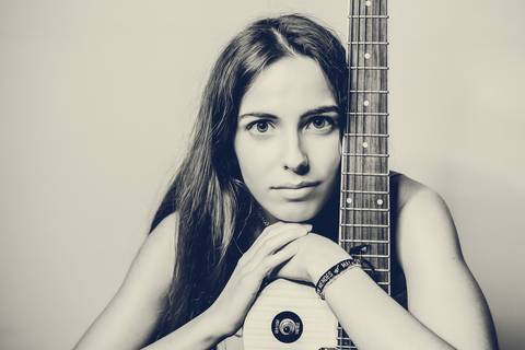 Retrato monocromático sentada com violão em pose elegante'