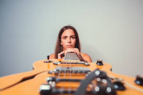 Mulher com violão e suéter listrado em estúdio claro'