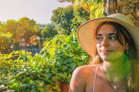 Mulher com chapéu em jardim verde com luz natural'