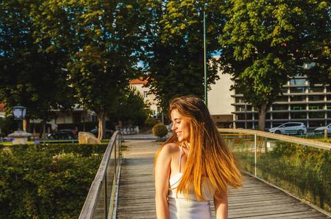 Mulher em passarela de madeira sobre lago ao entardecer'