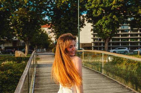 Mulher em vestido laranja caminhando em passarela sobre lago'