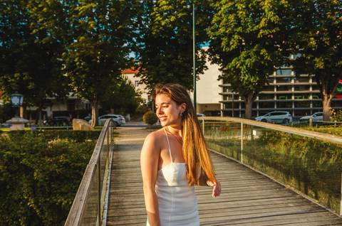 Mulher em vestido branco na passarela de madeira sobre lago'