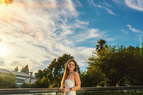 Mulher em vestido branco em parque com céu e árvores'