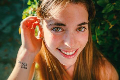 Close-up de mulher sorridente segurando flor vermelha'