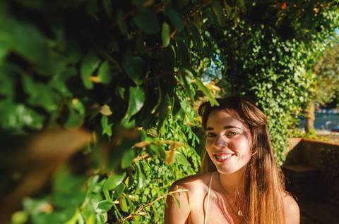Mulher sorridente em meio à vegetação do jardim ao ar livre'