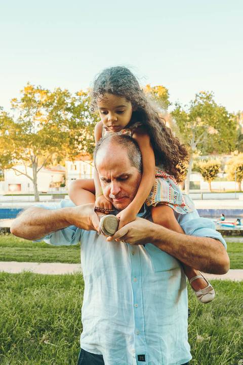 Pai em ambiente de piscina fazendo expressão divertida durante sessão fotográfica de família, retrato masculino descontraído com momento de diversão ao ar livre em parque aquático'