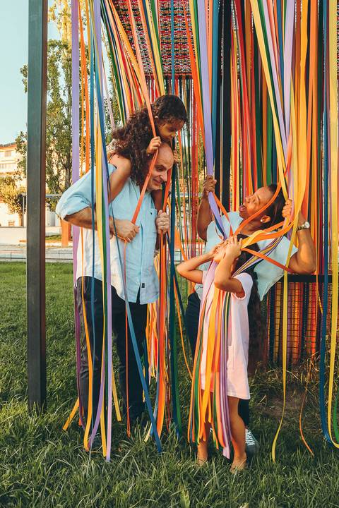 Mãe brincando com filha e abraçada durante sessão fotográfica de família em parque ao ar livre, retrato de mãe com filha rindo em ambiente descontraído com luz natural'