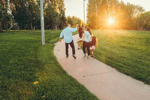Família posando junto a estrutura em parque ao pôr do sol durante sessão fotográfica ao ar livre, retrato familiar com crianças em ambiente de lazer com luz golden hour dourada'