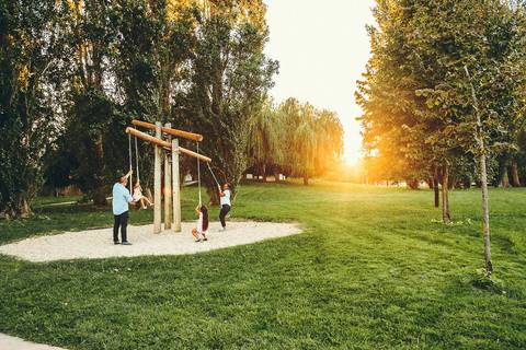 Menino em primeiro plano em estrutura de parque ao entardecer durante sessão fotográfica de família, retrato infantil individual em ambiente de lazer com luz golden hour natural'