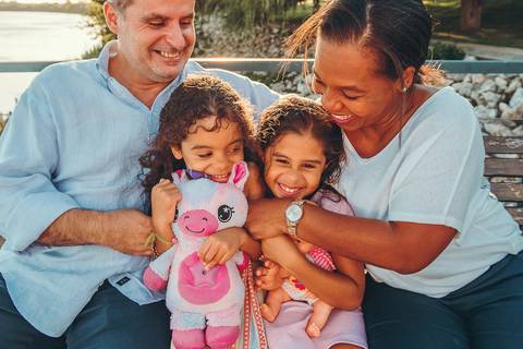 Dois pais com filhas pequenas em ambiente de pedras, sessão fotográfica ao ar livre com vista da natureza, retrato de família moderna e afetuosa durante golden hour'