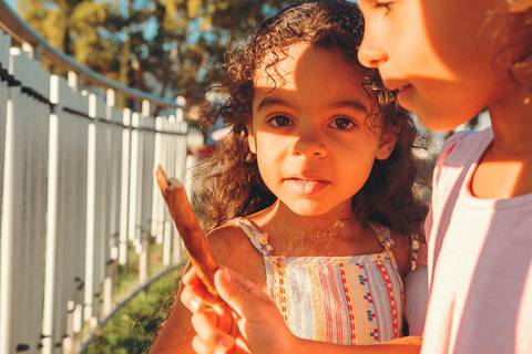 Menina sorrindo durante sessão de fotografia de família profissional ao entardecer, com luz dourada iluminando o rosto, retrato infantil ao ar livre em Vila Nova da Barquinha'