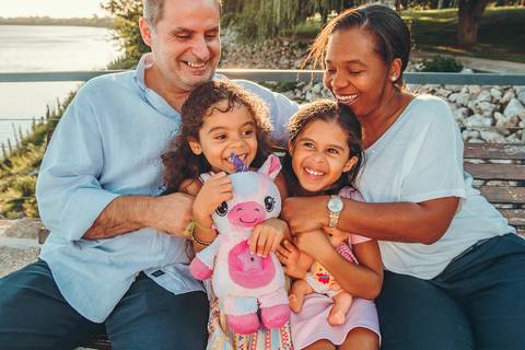 Família Teixeira posando junto à árvore em ambiente natural, sessão fotográfica em parque com luz golden hour, retrato familiar intergeneracional em Vila Nova da Barquinha'