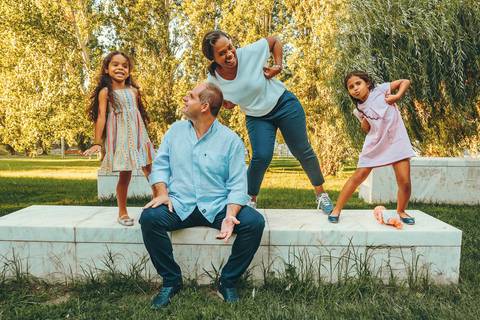 Família Teixeira brincando na grama ao entardecer em parque verde, sessão fotográfica de família com momentos calorosos e espontâneos, retrato de família com crianças alegres ao ar livre'