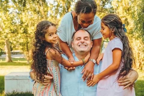 Mãe com filhas durante sessão fotográfica de família ao pôr do sol em ambiente com luz dourada, retrato de mães e filhos caloroso em parque natural ao ar livre'