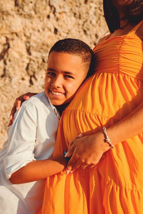 filho-menino-sorrindo-abançando-mãe-gravida-na-gravidez'