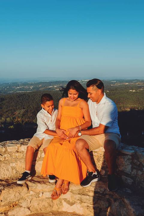 gravida-familia-pai-mãe-filho-se-olhando-em-castelo-de-ourém-na-muralha'