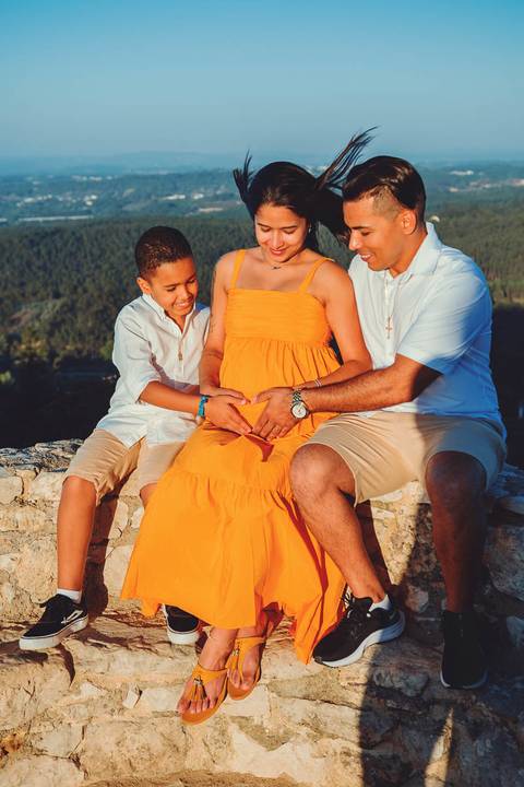 gravida-familia-pai-mãe-filho-se-olhando-em-castelo-de-ourém-na-muralha'