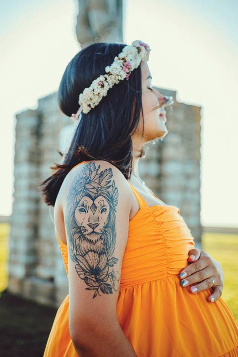 mulher-gravida-posando-de-perfil-mostrando-tatuagem-de-leoa-mãos-na-barriga'
