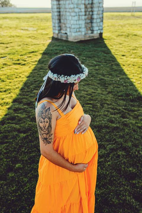 mulher-gestante-mãos-na-barriga-em-frente-a-estatua-no-patio-do-castelo-de-ourem'