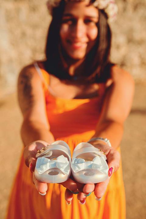 gravida-segurando-sapatinho-de-bebe-nas-mãos'