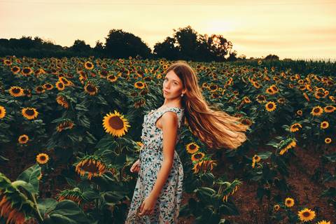 Mulher com cabelo comprido em vestido floral em um campo de girassóis'