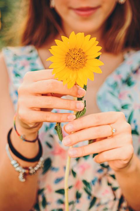 Mulher com cabelo comprido em vestido floral em um campo de girassóis'