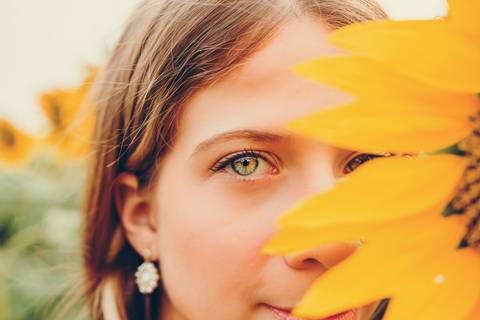 Capa - Close-up profissional do rosto com foco nos olhos e girassol ao fundo - Fotografia Duo Capuano, Riachos'