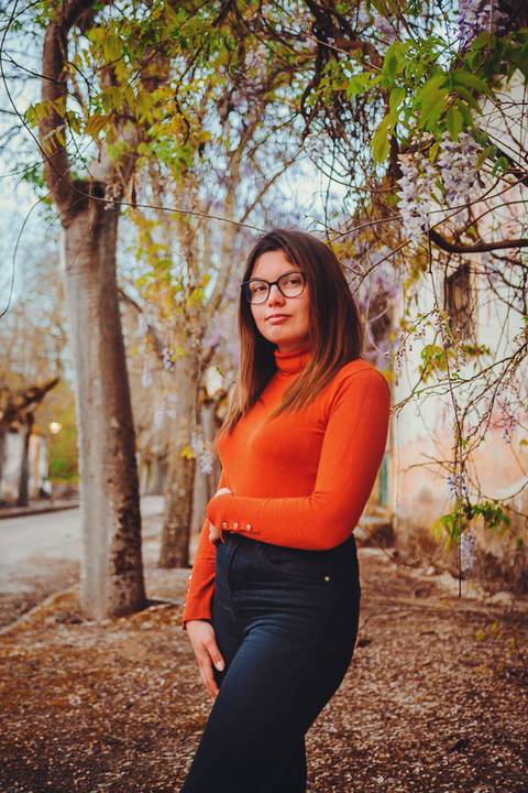 Myriam Correia de look laranja numa pose confiante com vegetação ao fundo durante sessão de retrato feminino na Quinta da Cardiga, Golegã. Energia e personalidade num retrato marcante. Duo Capuano.'