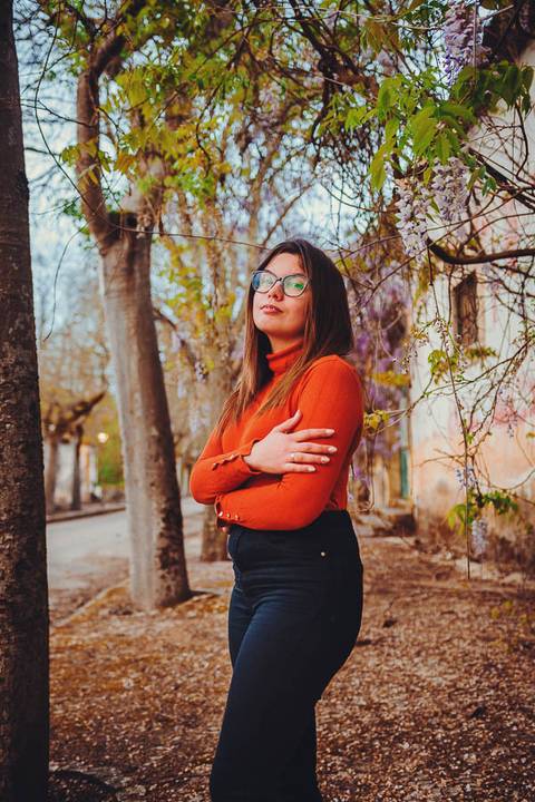 Myriam Correia de look laranja com braços cruzados em pose confiante durante sessão de retrato feminino na Quinta da Cardiga, Golegã. Determinação e estilo num único olhar. Duo Capuano Fotografia.'
