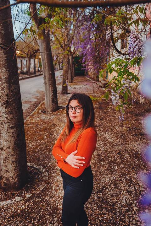 Myriam Correia de look laranja junto a uma parede de pedra durante sessão de retrato feminino na Quinta da Cardiga, Golegã. A textura do ambiente histórico como cenário ideal. Duo Capuano Fotografia.'