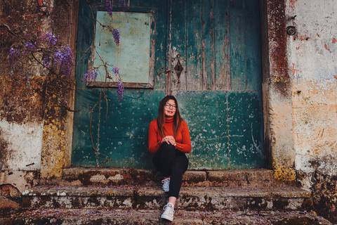 Myriam Correia sentada junto a uma porta histórica verde durante sessão de retrato feminino na Quinta da Cardiga, Golegã. O cenário arquitectónico como moldura perfeita. Duo Capuano Fotografia.'