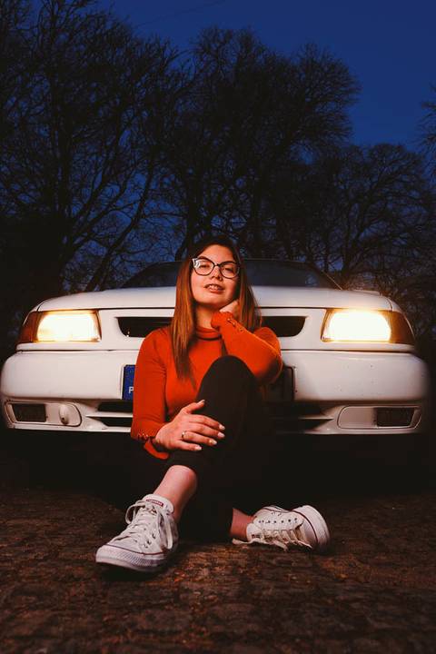 Myriam Correia de look laranja à frente do seu Seat Ibiza com faróis acesos durante sessão de retrato noturno na Quinta da Cardiga, Golegã. A luz dos faróis como cenário dramático. Duo Capuano.'