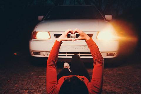 Myriam Correia com mãos em coração à frente dos faróis do Seat Ibiza durante sessão de retrato noturno na Quinta da Cardiga, Golegã. Amor pelo carro expresso num gesto único. Duo Capuano Fotografia.'